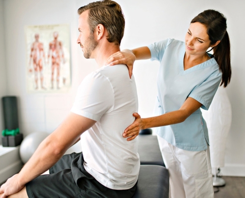 A physiotherapist applying manual therapy to a back man